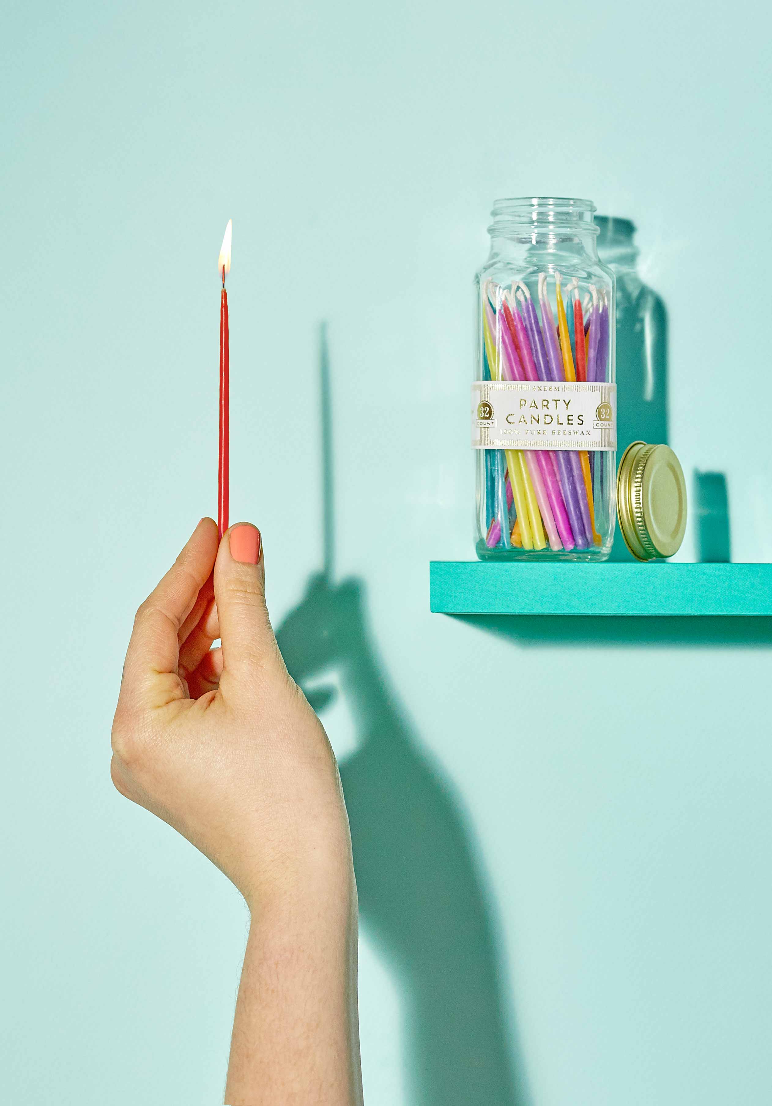 Party Candles with one lit candle held by a woman's hand